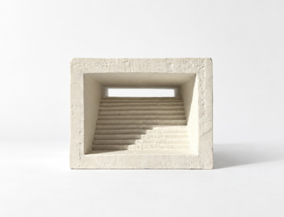 Plaster model photographed front-on against a plain white background, showing a stepped interior through a deep rectangular opening